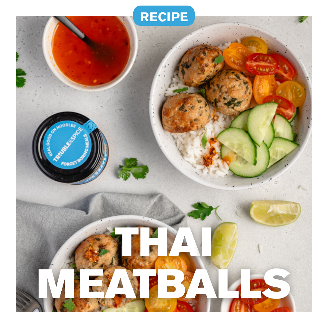 Bowl of Thai meatballs with rice, cucumber, and tomatoes, served with sweet chilli dipping sauce and Trouble & Spice chilli oil (chili olie) on the side.