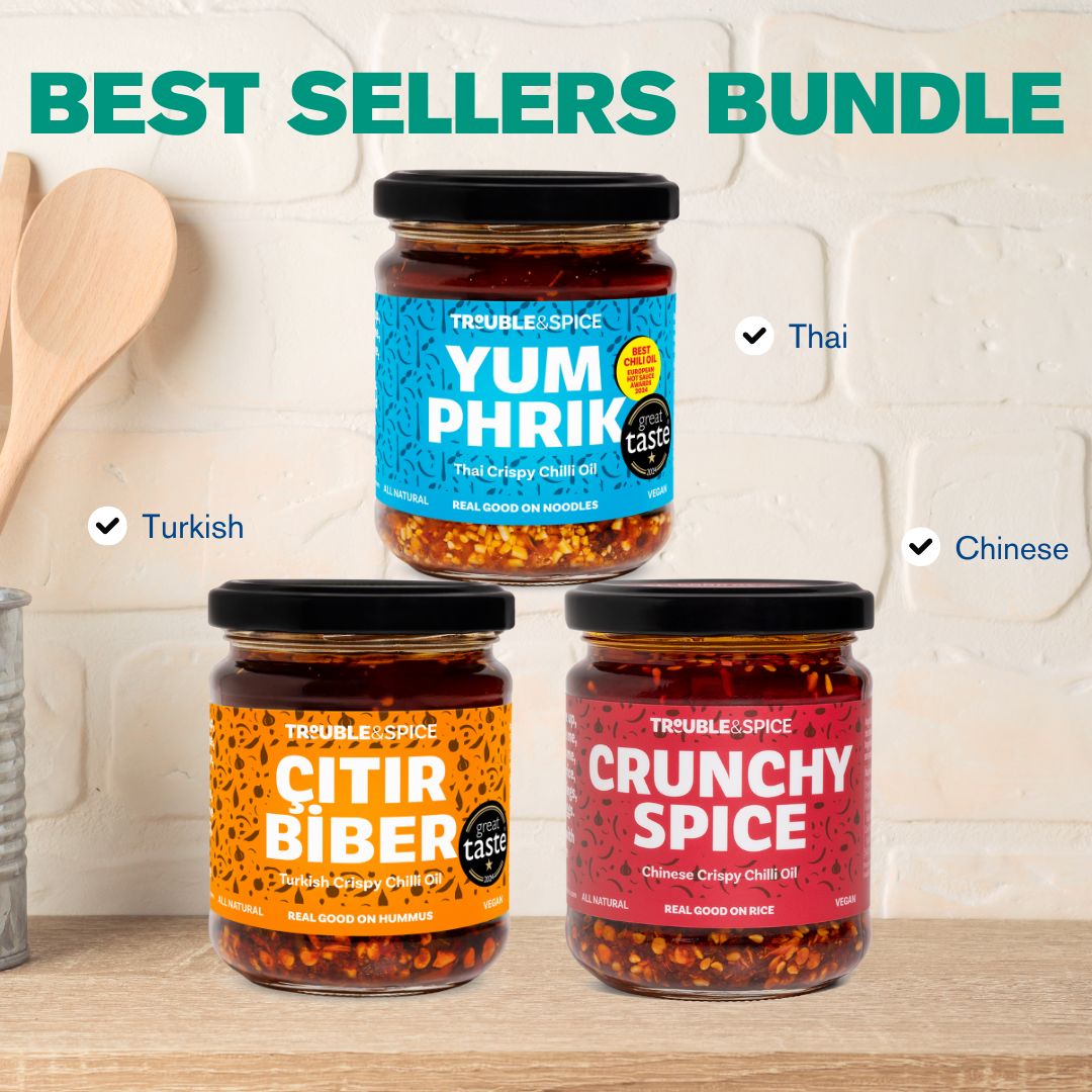 Three jars of Trouble & Spice chilli oils - chili olie labeled “Yum Phrik” (Thai), “Çıtır Biber” (Turkish), and “Crunchy Spice” (Chinese) displayed on a kitchen counter under the heading “Best Sellers Bundle.