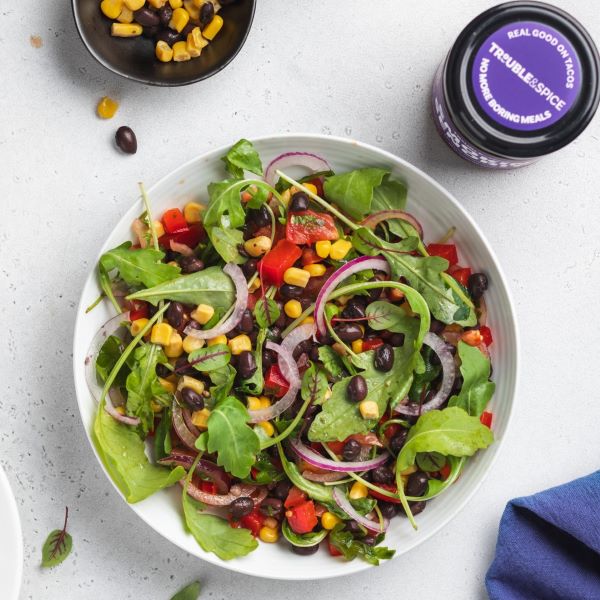 Fresh Mexican salad with corn, black beans, red onion, and greens, served with Trouble & Spice chilli oil - chili olie.