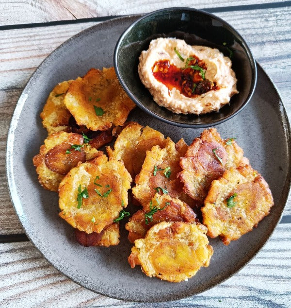 Crispy golden tostones served on a grey plate with a smoky chili-infused dip made with Smokin Senorita salsa macha by Trouble & Spice.